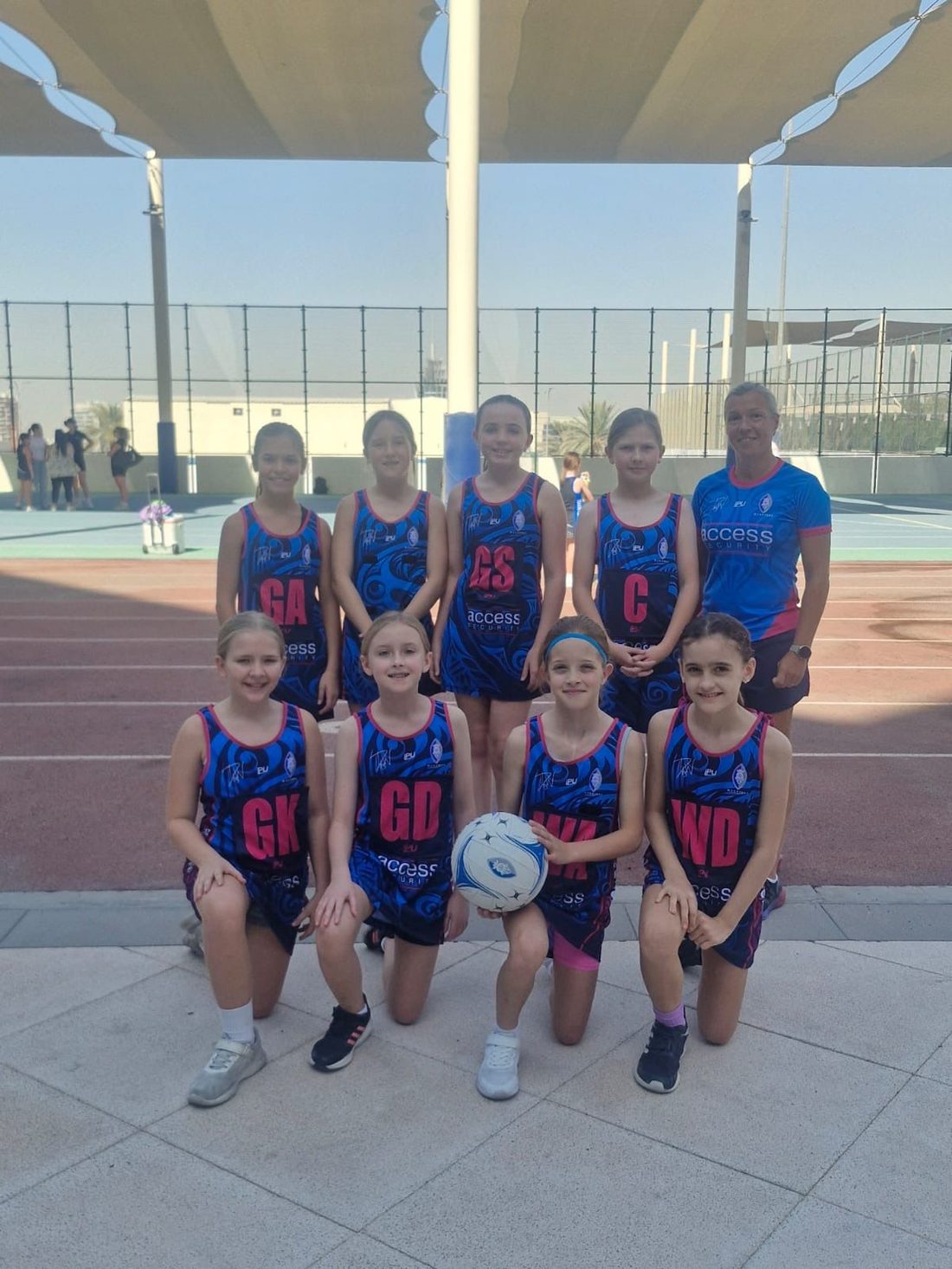 Dubai Warriors netball team with position bibs and their coach